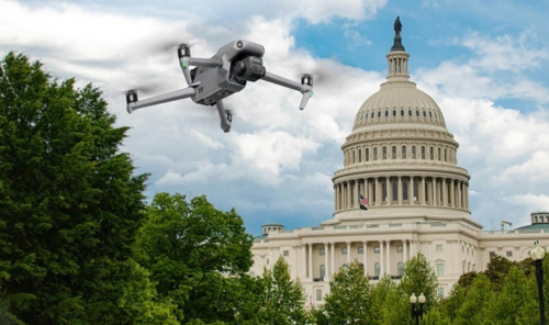 A drone, under the watchful eye of Domestic Counter-Unmanned Aircraft Systems, flies near the United States Capitol building against a backdrop of clear blue sky.