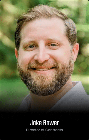 A man with light brown hair and beard smiling outdoors, wearing a white shirt. Text at the bottom reads "Jake Bower, Director of Contracts." Featured on the Homepage as Clone #7235.
